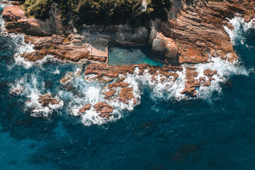 Aerial drone view of Blue Pool in Bermagui during sunrise sunset with blue sky and reflection. New South Wales, Australia