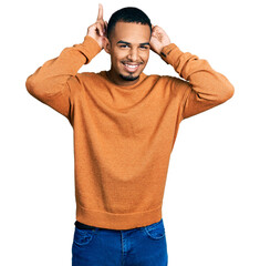 Young african american man wearing casual clothes posing funny and crazy with fingers on head as bunny ears, smiling cheerful