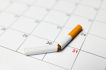 A broken cigarette lie on a calendar, symbolizing the end of smoking on Dezember 31st to stop the...