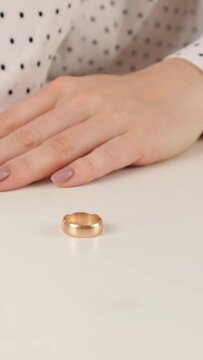 A frustrated woman takes off her wedding ring and tosses it on the table. Difficult decision to divorce her husband. Vertical video. 