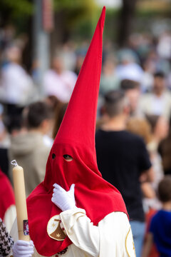 Nazareno, bearer in a procession of the easter week in Seville, andalusia, Spain. 2024 Semana Santa. Red hood, procession of 23.03.2024
