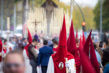 Nazareno, bearer in a procession of the easter week in Seville, andalusia, Spain. 2024 Semana Santa. Red hood, procession of 23.03.2024 - obrazy, fototapety, plakaty
