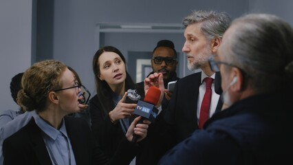 Busy American presidential candidate answers press questions and gives interview for media walking in parliament hallway. Confident politician surrounded by journalists. Election coverage. Slow motion