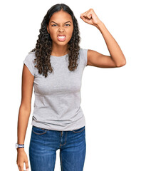 Young african american girl wearing casual clothes angry and mad raising fist frustrated and furious while shouting with anger. rage and aggressive concept.