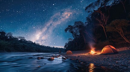 Tents by a river with a roaring campfire under a star-filled sky and the Milky Way visible.