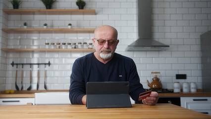 Senior man enter credit card number on tablet computer for shopping online, makes secure easy...