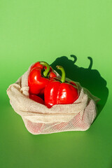two red bell peppers in a cotton shopping bag. vertical photo