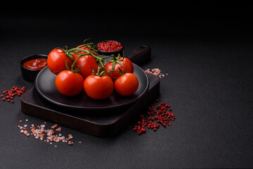 Fresh red cherry tomatoes on a branch on a dark concrete background
