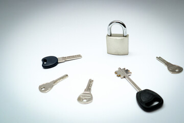 One padlock with many another keys. Many keys and one lock as concept. Different metal keys and one hinged steel padlock on a white background.
