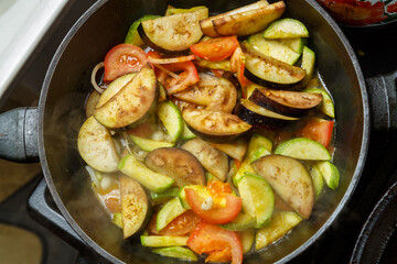 Vegetables fried in spices in a frying pan in oil on the stove