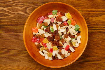Mix of dried fruits and nuts on a wooden plate on the table
