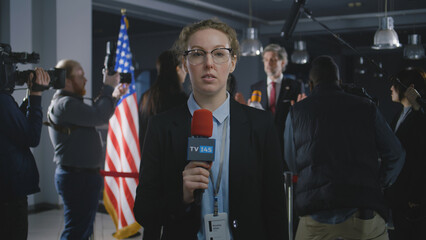 Caucasian anchorwoman reports breaking news live from government building. Female journalist leads...