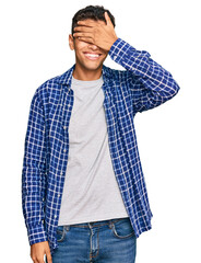 Young handsome african american man wearing casual clothes smiling and laughing with hand on face covering eyes for surprise. blind concept.