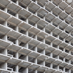 A large multi-storey apartment building is under construction, with a grey facade and a pattern of holes. Full-frame background. Low angle view,