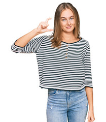 Fototapeta premium Beautiful blonde woman wearing casual clothes smiling and confident gesturing with hand doing small size sign with fingers looking and the camera. measure concept.