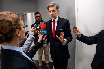 Busy politician answers press questions, gives interview for news in corridor of government...