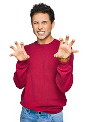 Young handsome man wearing casual clothes smiling funny doing claw gesture as cat, aggressive and...