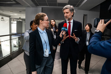 Busy politician answers press questions, gives interview for news in corridor of government...