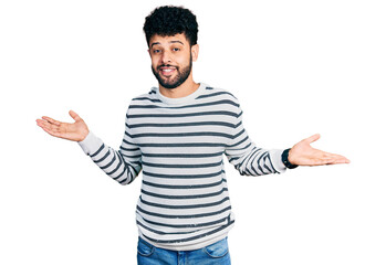Young arab man with beard wearing casual striped sweater clueless and confused expression with arms...