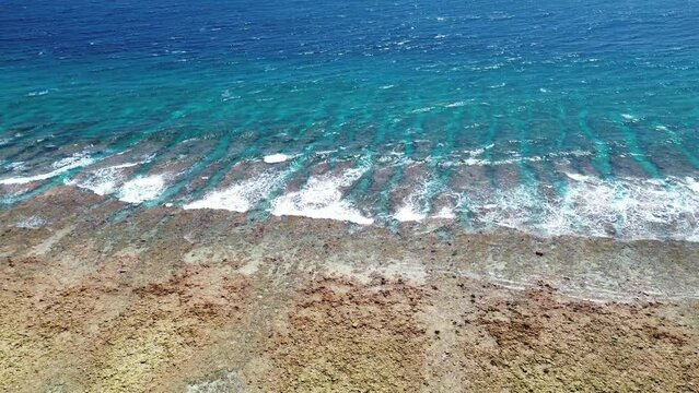 Drone view from above of the coral reefs and waves on the beaches of the Maldives.