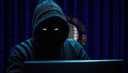 Hacker in a dark hoodie sitting in front of a monitors with Kentucky flag and background cyber security concept