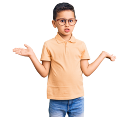 Little cute boy kid wearing casual clothes and glasses clueless and confused expression with arms and hands raised. doubt concept.
