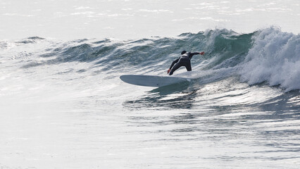 A male surfer riding a wave  at Polzeath in Cornwall