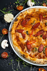 pizza alla diavola with spicy salami, mozzarella, tomato and basil. view from top. black stone background