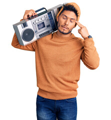 Handsome latin american young man holding boombox, listening to music shooting and killing oneself pointing hand and fingers to head like gun, suicide gesture.