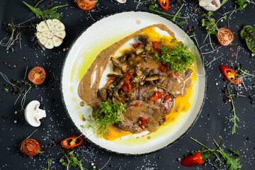 Tender veal with mushrooms is served in deep dish, filled with thick fragrant gravy. Tender meat is garnished with stewed vegetables and herbs.