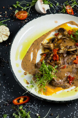 Tender veal with mushrooms is served in deep dish, filled with thick fragrant gravy. Tender meat is garnished with stewed vegetables and herbs.