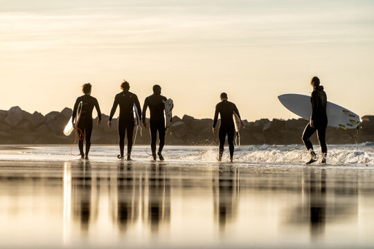 El Camino de las Olas Captura la sensación de libertad y al atardecer mientras los surfista avanzan por la suave arena de la playa.