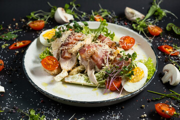 Fresh caesar salad in white plate on dark wooden table. Top view.