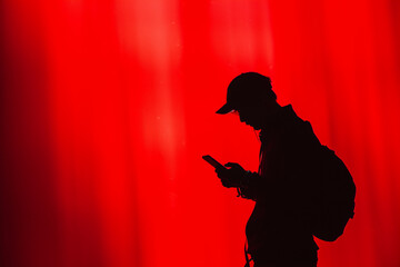 Silhouette of a Person with Smartphone on Vibrant Red Background