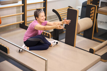 Smiling woman stretching after injury during recovery in rehabilitation gym