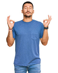 Handsome man with tattoos wearing casual clothes relax and smiling with eyes closed doing meditation gesture with fingers. yoga concept.