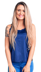 Young beautiful blonde woman wearing casual sleeveless t-shirt looking positive and happy standing and smiling with a confident smile showing teeth