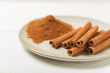Cinnamon sticks on a textured wooden background. Cinnamon roll. Spicy spice for baking, desserts and drinks. Fragrant ground cinnamon. cinnamon powder Close-up. Place for text. copy space