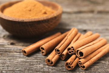 Cinnamon sticks on a textured wooden background. Cinnamon roll. Spicy spice for baking, desserts and drinks. Fragrant ground cinnamon. cinnamon powder Close-up. Place for text. copy space