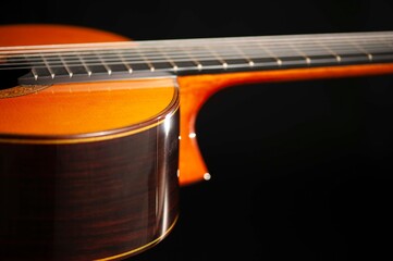 Classical Spanish flamenco guitar close up, dramatically lit isolated on black background with copy...