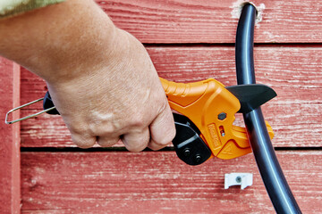 When installing plumbing system for drinking and irrigation water, plumber cuts pipe with ratchet...