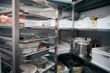 Focus of dishes on shelves in blurred refrigerator storage in restaurant