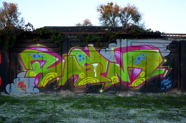 The old wall decorated with paint stains in the style of street art culture. Colorful background of full graffiti painting artwork with bright aerosol outlines on wall. Colored background texture