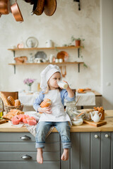 Girl cook 3 years old in a beautiful kitchen, in a chef's hat, in an apron, daylight