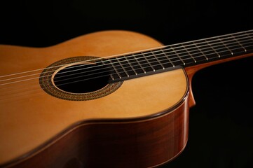 Classical Spanish flamenco guitar close up, dramatically lit isolated on black background with copy space.