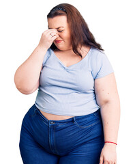 Young plus size woman wearing casual clothes tired rubbing nose and eyes feeling fatigue and...