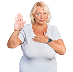 Middle age blonde woman wearing casual white t shirt swearing with hand on chest and open palm,...