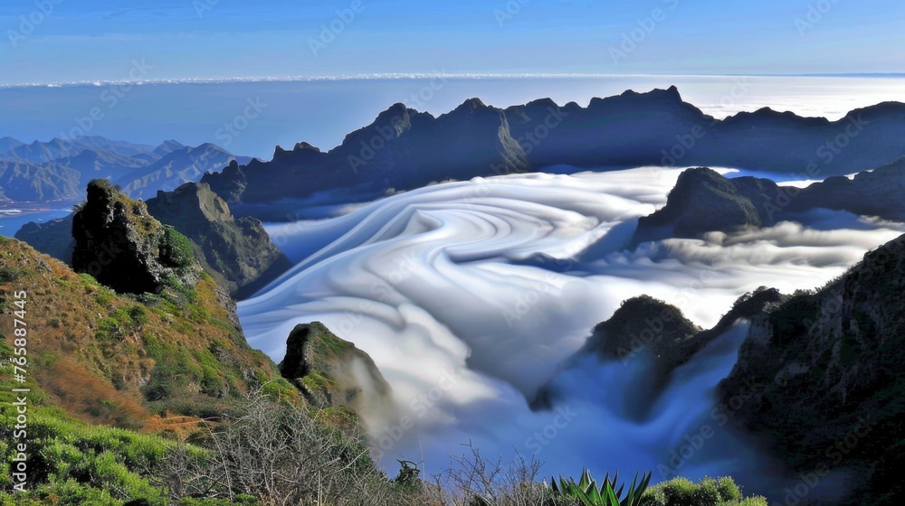 Poster a view of a mountain range covered in a layer of white snow and low lying clouds in the foreground, 