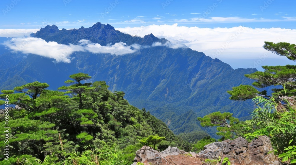 Poster a view of a mountain range with trees in the foreground and a few clouds in the sky in the backgroun