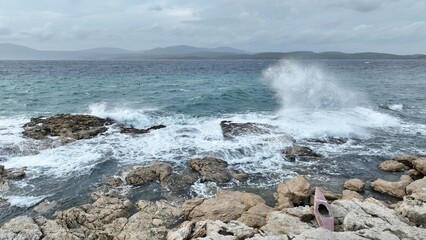 The colorful waters of the ocean swirl around the rocky and beautiful coastline. Sea waves passing...